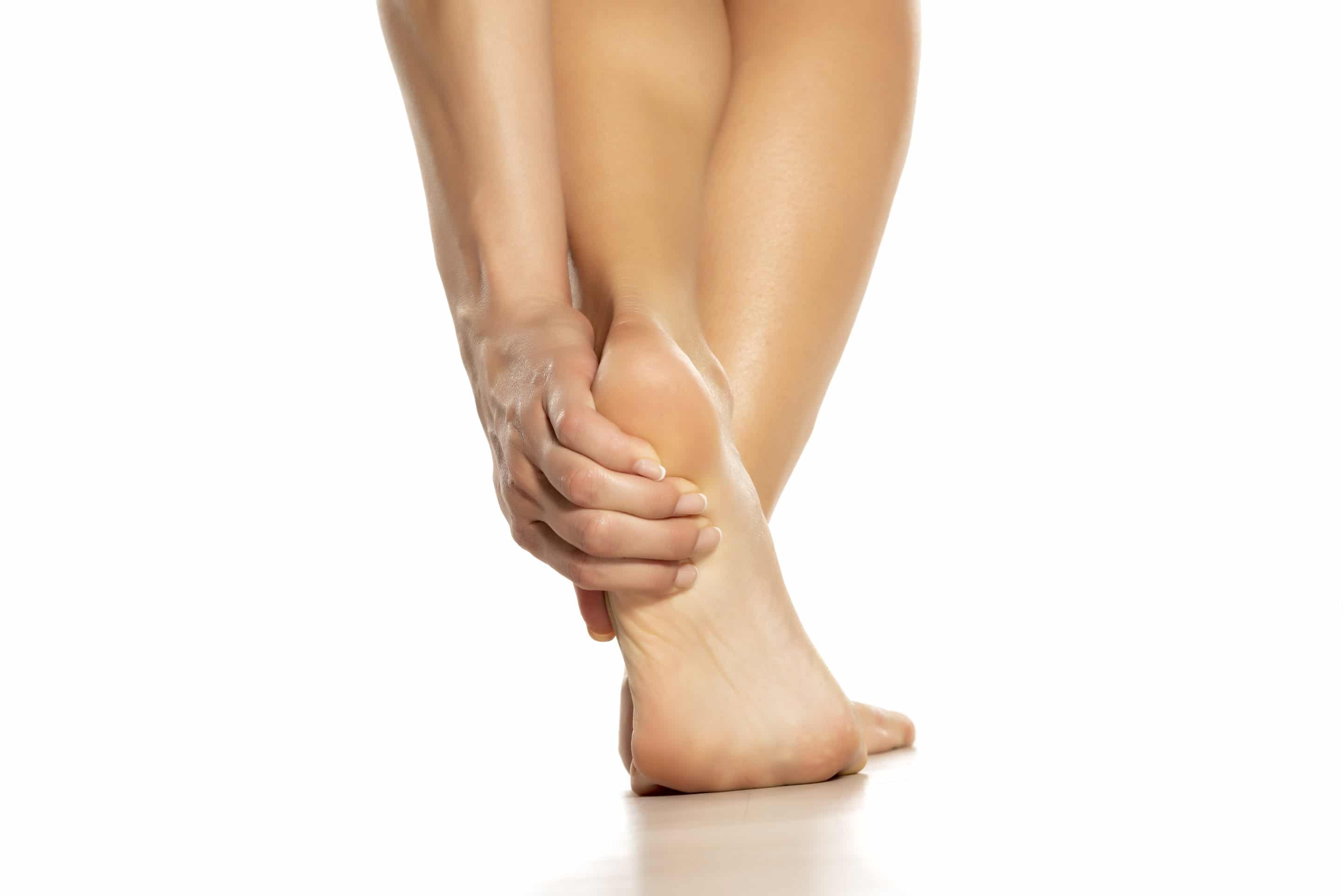 woman holding her painful heel on white background